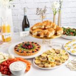 A beautifully arranged food spread for a bridal shower, featuring various brunch dishes and drinks.