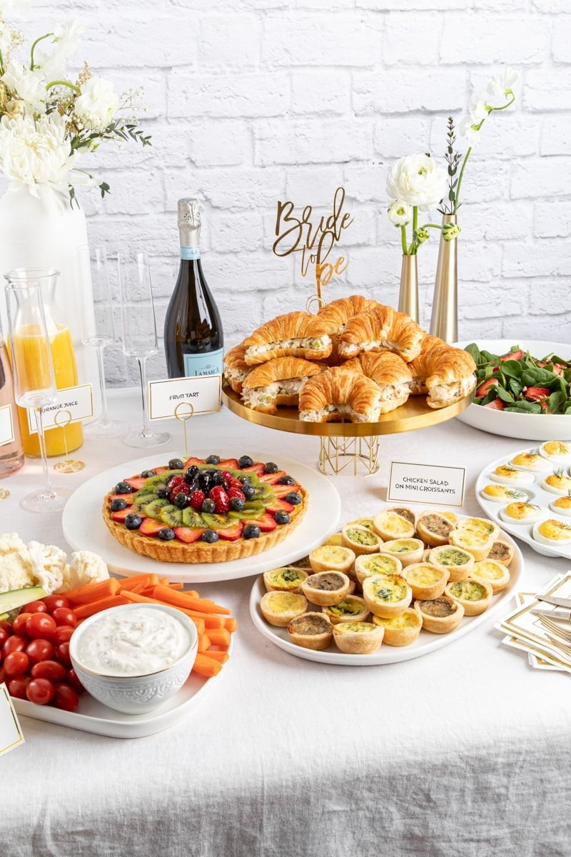 A beautifully arranged food spread for a bridal shower, featuring various brunch dishes and drinks.