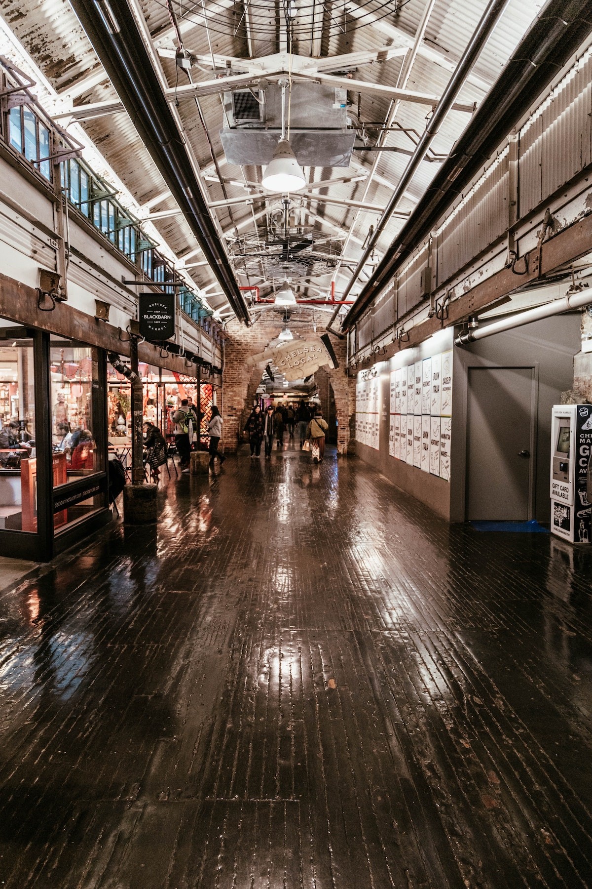 A bustling interior view of Chelsea Market showcasing diverse food stalls and crowds of people.