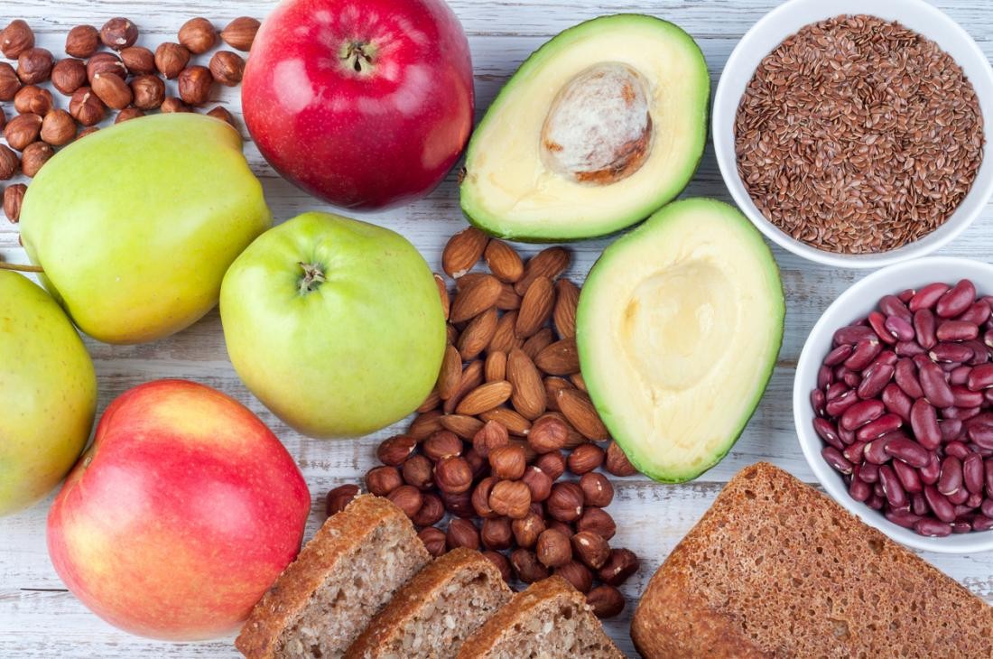 A colorful array of high-fiber plant-based foods including fruits, vegetables, legumes, nuts, seeds, and whole grains, promoting healthy digestion.