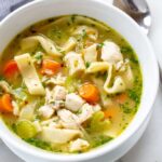 A comforting bowl of homemade chicken noodle soup with visible egg noodles and chicken pieces.