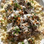 A generous serving of Mansaf, featuring rice, yogurt sauce, and tender lamb