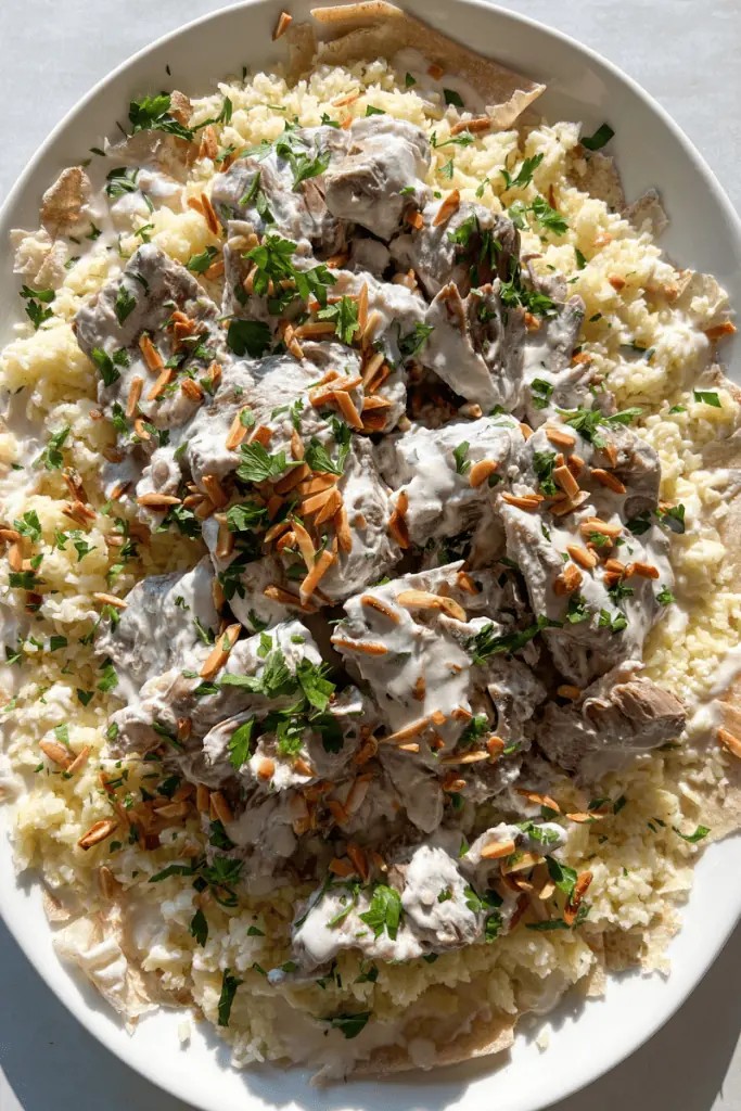 A generous serving of Mansaf, featuring rice, yogurt sauce, and tender lamb