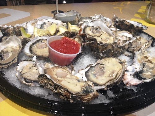 A half-order of enormous oysters served at Whole Foods happy hour, showcasing the generous portion and fresh seafood deal.