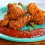 A plate of golden conch fritters, served with a dipping sauce, showcasing the crispy exterior and tender interior