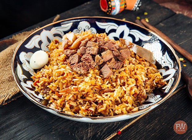 A plate of Uyghur Polo, showcasing rice, carrots, and lamb, a signature dish of Xinjiang, China