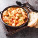 A steaming bowl of Brodetto, a traditional Croatia food fish stew, with visible chunks of fish and rich tomato-based broth.