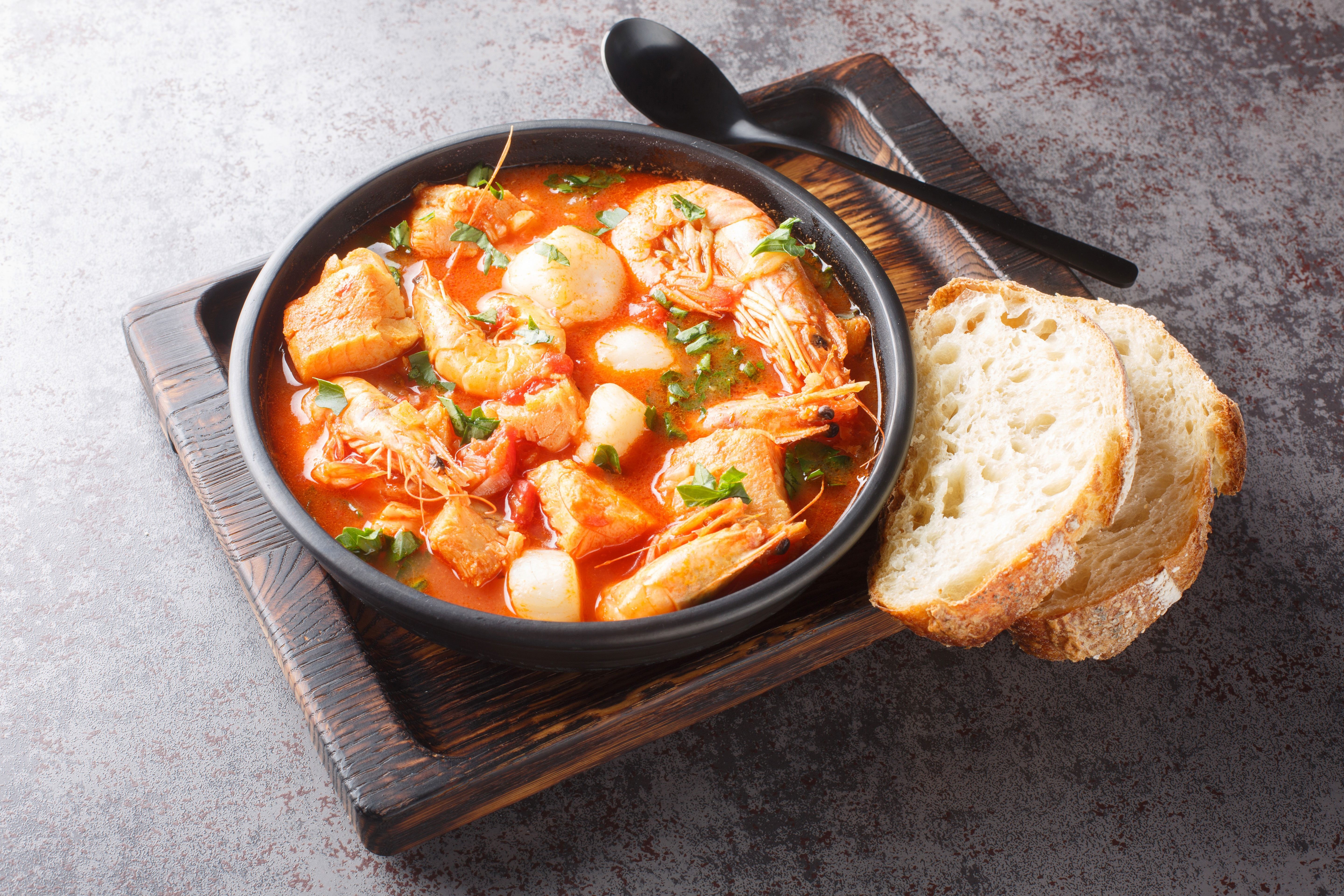 A steaming bowl of Brodetto, a traditional Croatia food fish stew, with visible chunks of fish and rich tomato-based broth.