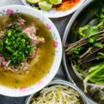 A steaming bowl of Pho, showcasing the rich broth and fresh herbs