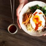 A vibrant bowl of Bibimbap with various vegetables, egg, and gochujang.