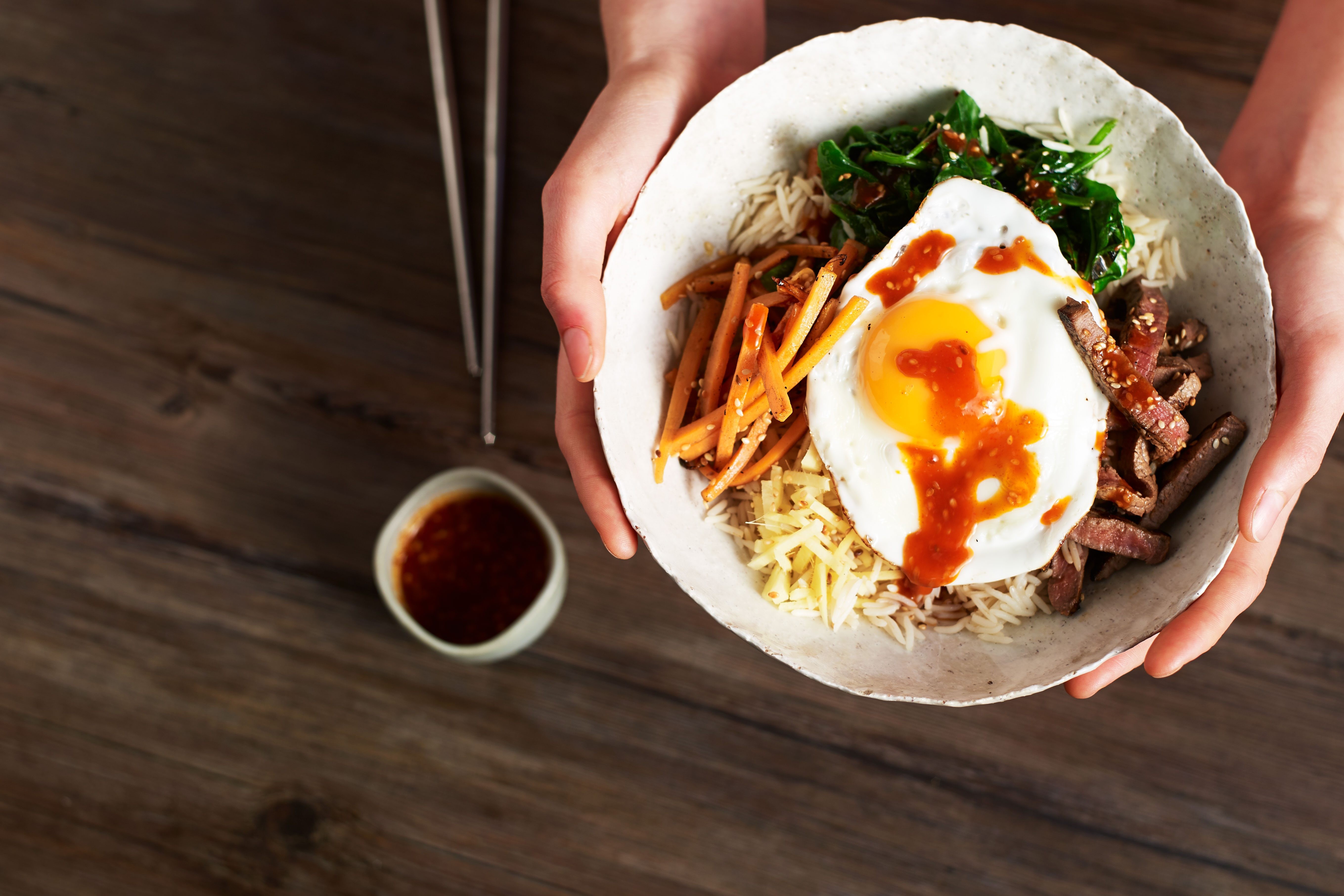 A vibrant bowl of Bibimbap with various vegetables, egg, and gochujang.