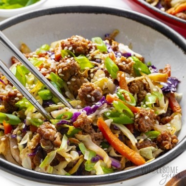 A vibrant bowl of egg roll in a bowl, accompanied by chopsticks.