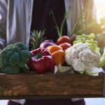 A vibrant display of fresh, low-carb fruits and vegetables in a crate, highlighting the colorful and healthy produce allowed on the Atkins diet.