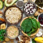 A vibrant display of magnesium-rich foods including bananas, avocados, nuts like almonds and walnuts, seeds such as chia and pumpkin, leafy greens like spinach, lentils, peas, oats, rice, dried apricots, and kelp, highlighting diverse dietary sources of magnesium.