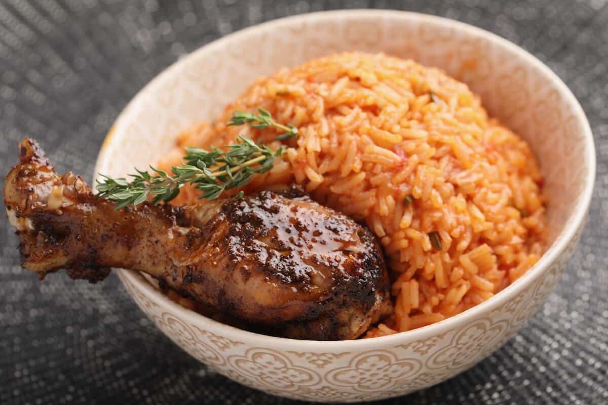 A vibrant plate of Jollof Rice, a staple Nigerian African food dish, showcasing its reddish hue and steam, surrounded by serving utensils.