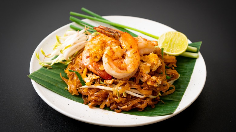 A vibrant plate of Pad Thai, showcasing noodles, shrimp, tofu, peanuts, and lime.