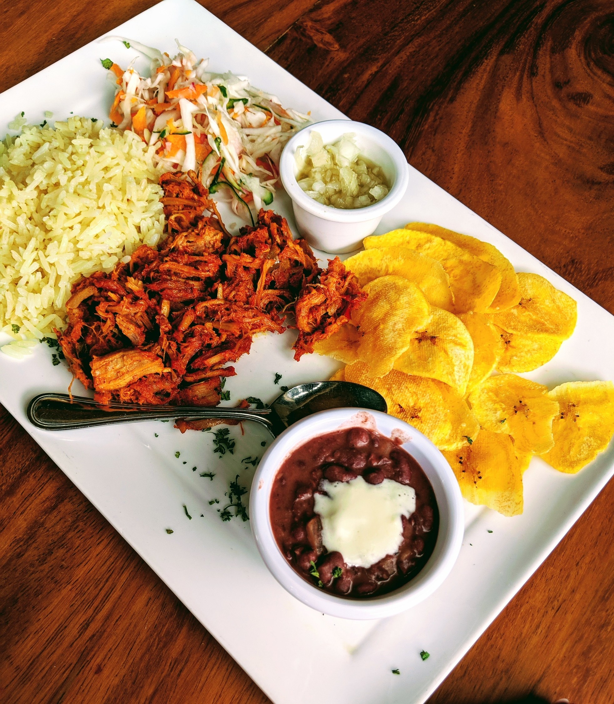 A vibrant plate of typical Nicaraguan food, showcasing gallo pinto, plantains, and cheese on a rustic brown table.