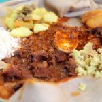 A vibrant spread of Ethiopian dishes on injera, showcasing the communal style of eating