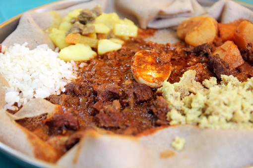 A vibrant spread of Ethiopian dishes on injera, showcasing the communal style of eating