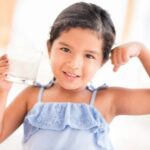 A young girl happily drinking milk, symbolizing strength and healthy development.