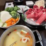 An enticing individual hot pot filled with a variety of meats and fresh vegetables, showcasing the customizable and interactive dining experience at Bronze Empire.