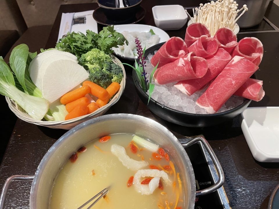 An enticing individual hot pot filled with a variety of meats and fresh vegetables, showcasing the customizable and interactive dining experience at Bronze Empire.