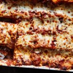 An overhead image of lasagna in a baking dish, with a couple of slices taken out.