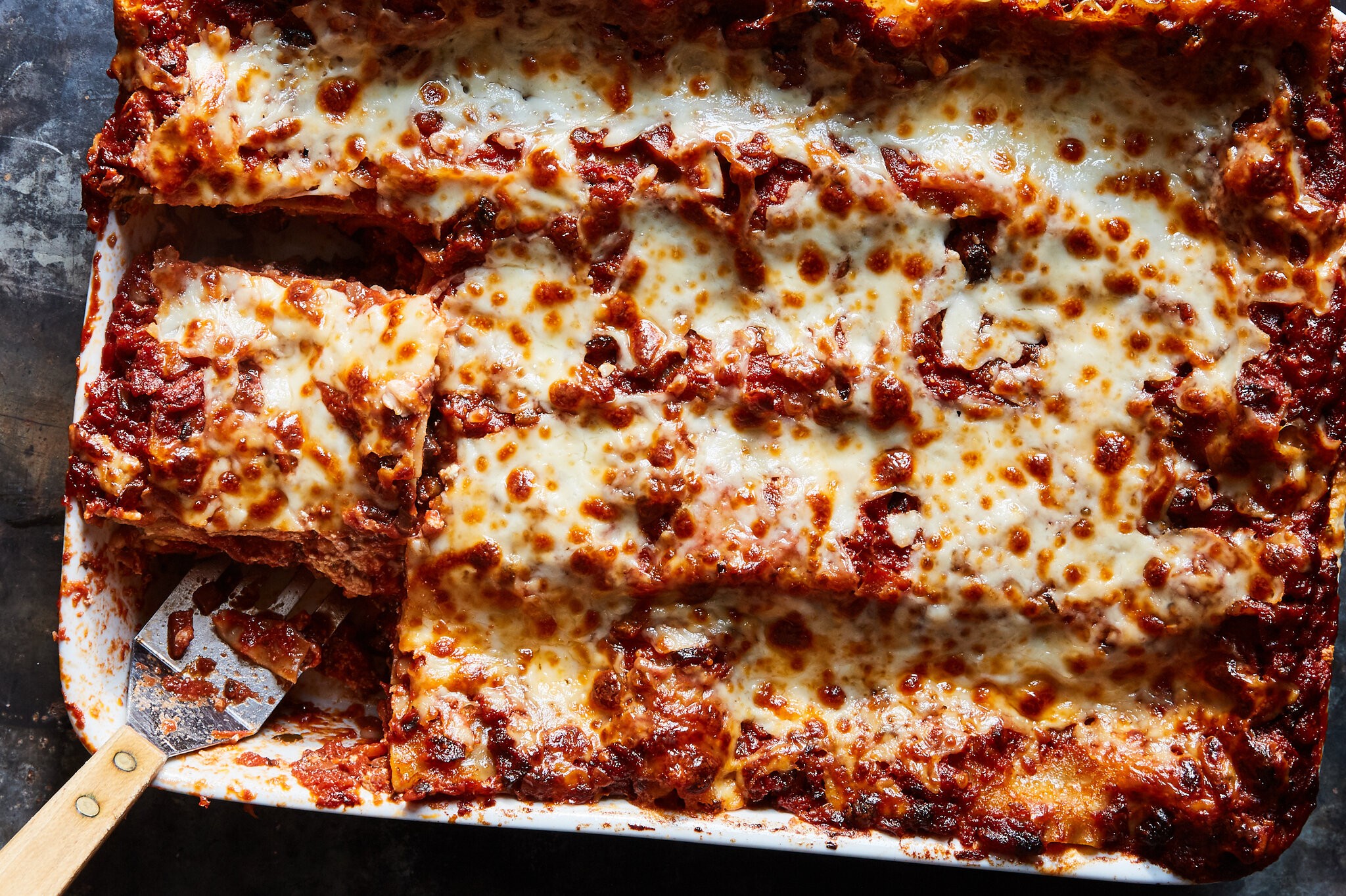 An overhead image of lasagna in a baking dish, with a couple of slices taken out.