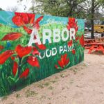 An overview of Arbor Food Park in Austin, Texas, showcasing a variety of food trucks and outdoor picnic table seating areas.