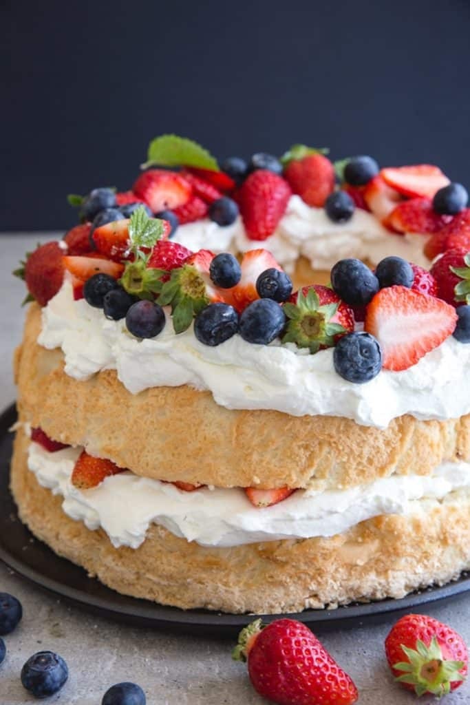 Angel food cake on a black plate, showcasing its light and airy texture.