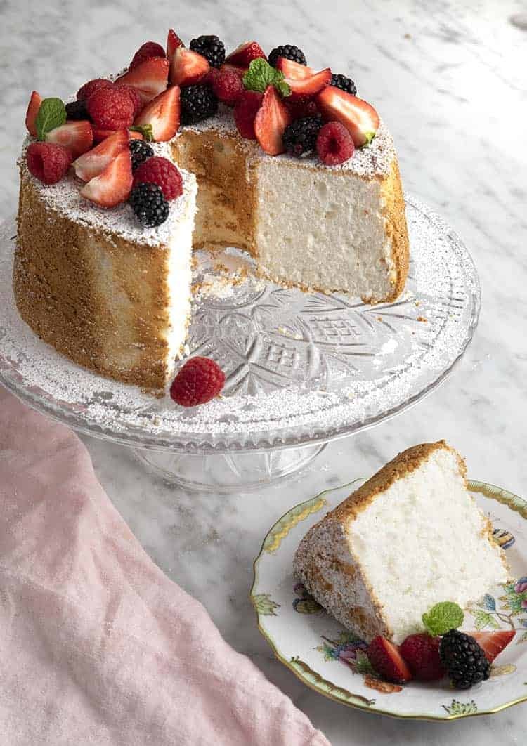 Angel food cake with fresh berries and powdered sugar on a cake stand