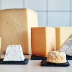 Assortment of cheeses displayed on a wooden table, showcasing variety in color and texture