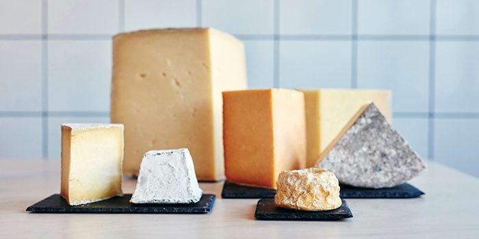 Assortment of cheeses displayed on a wooden table, showcasing variety in color and texture