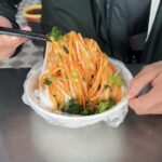 Bowl of Liang Pi cold noodles, a classic Xian food, showcasing the noodles and vegetable toppings.