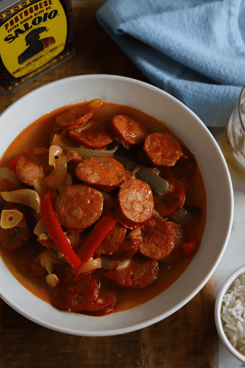 Bowl of linguiça with onions and peppers in sauce, a Cape Verde food sausage dish