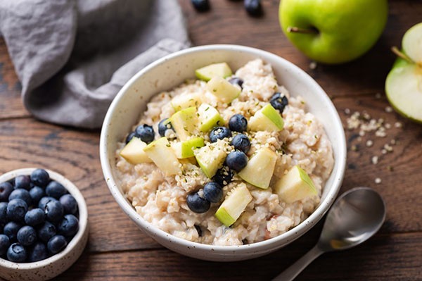 Bowl of oatmeal with blueberries and apple, berries, and apple slices