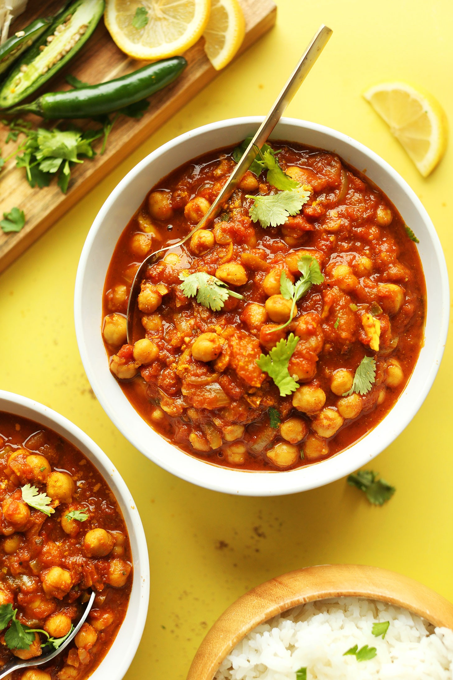 Bowls of our homemade gluten-free vegan Chana Masala recipe with rice, jalapeno, and lemons