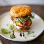 Close-up of a peach and goat cheese turkey burger on a plate, highlighting the juicy peach and melted goat cheese