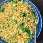 Close-up of fluffy couscous garnished with fresh herbs, showcasing its texture and appetizing appearance