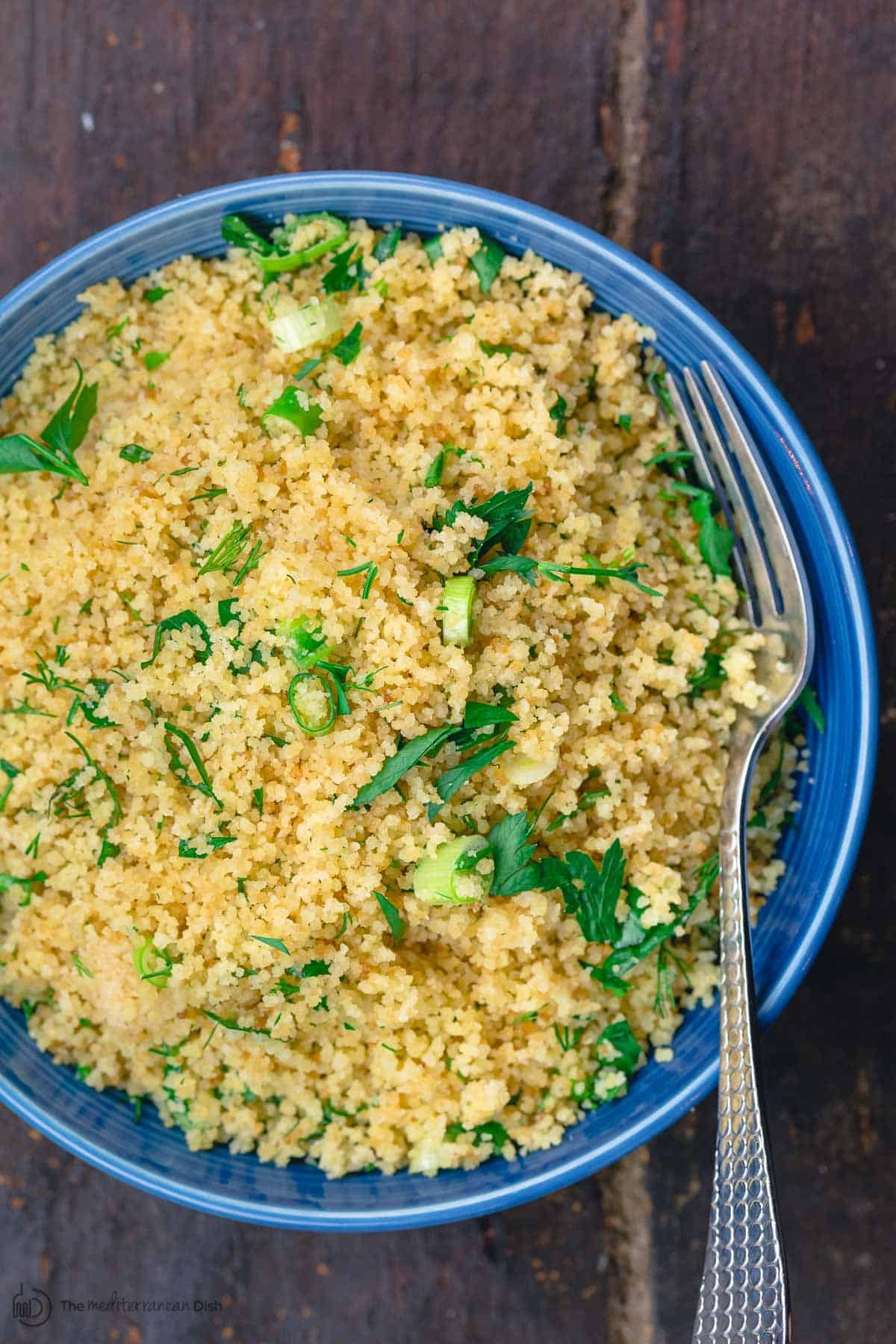 Close-up of fluffy couscous garnished with fresh herbs, showcasing its texture and appetizing appearance