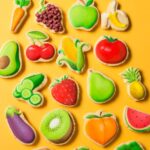 Close up of fruit and vegetable emoji cookies including corn, broccoli, coconut, kiwi, carrot and strawberry