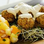 Close-up of raw falafel balls with alfalfa sprouts and a side of mango salsa, showcasing a vibrant and healthy food way