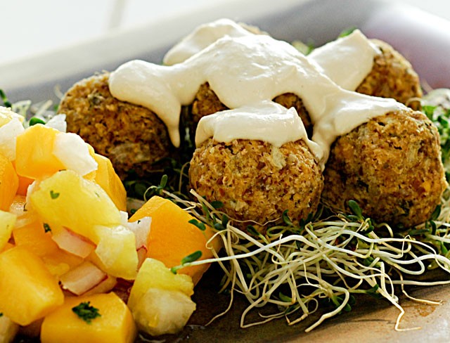 Close-up of raw falafel balls with alfalfa sprouts and a side of mango salsa, showcasing a vibrant and healthy food way