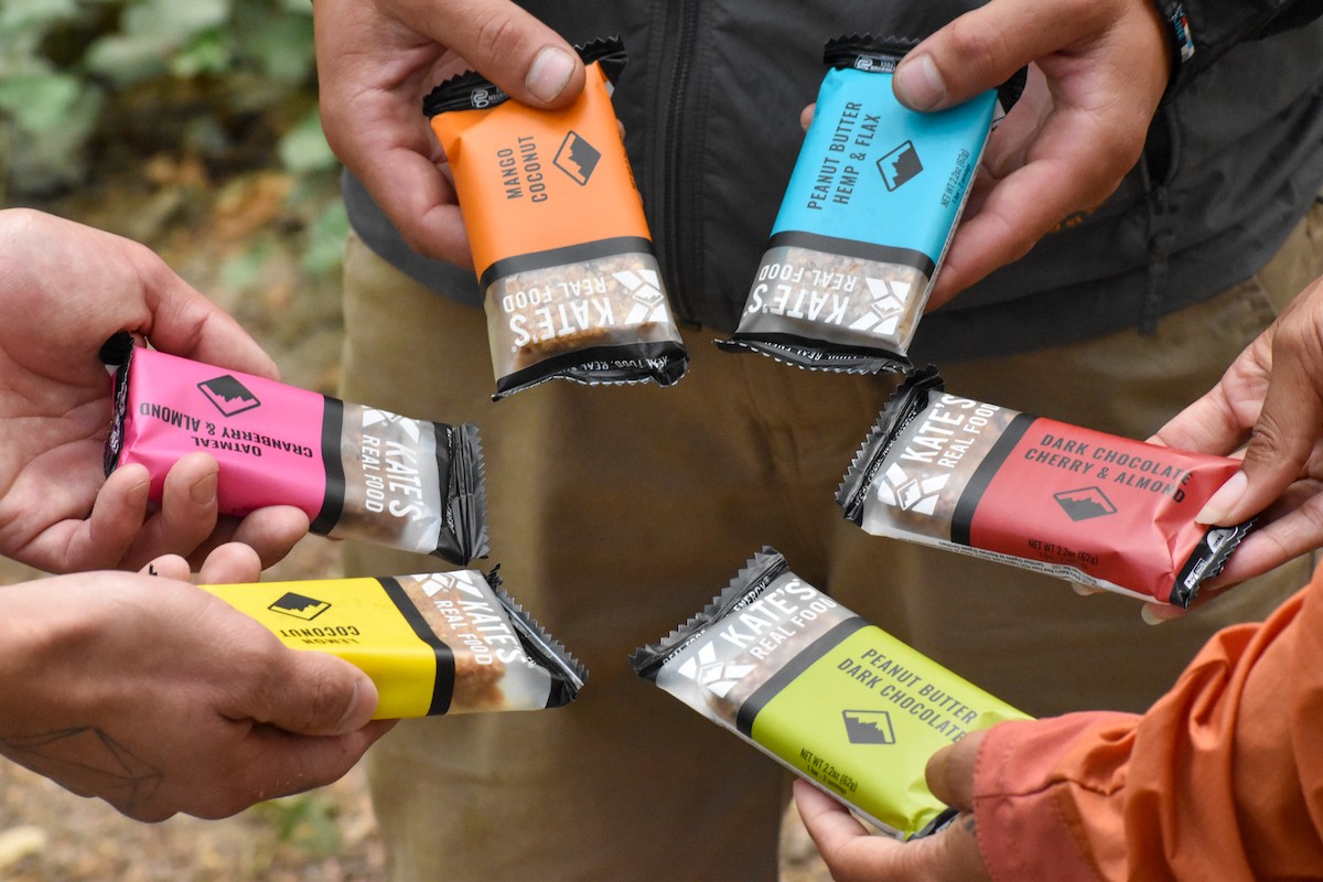 Close-up of two Kate's Real Food bars in hands, showcasing the packaging and texture