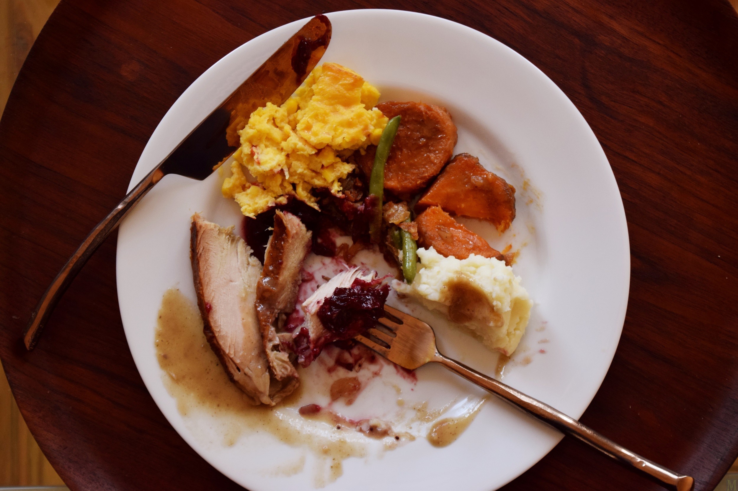 Close-up shot of a fully cooked and packaged Whole Foods Thanksgiving turkey, surrounded by various side dishes in black containers.