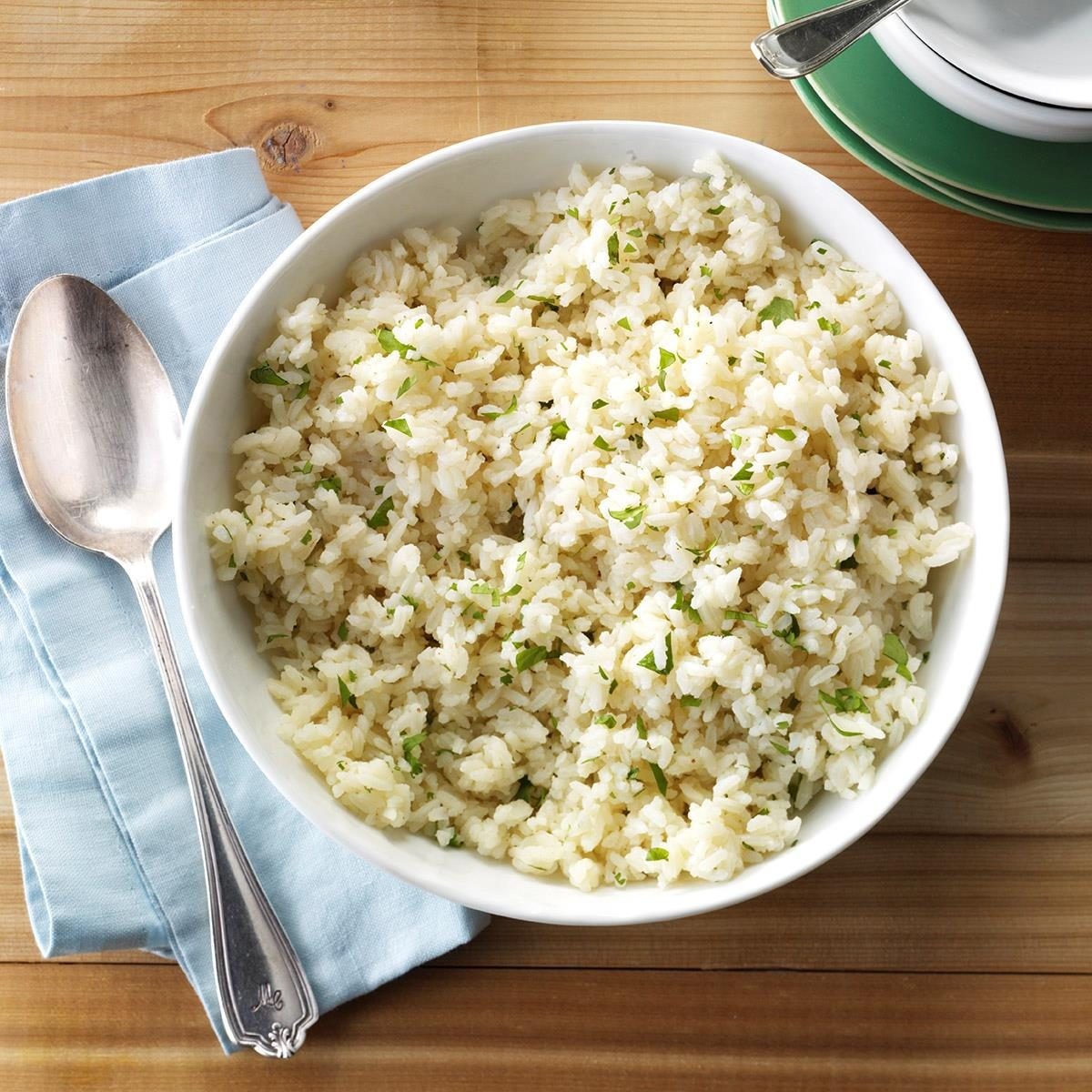 Close-up shot of cilantro lime rice in a white bowl, garnished with lime wedges and cilantro sprigs.