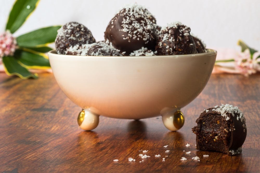 close up shot of dark chocolate almond truffles on a white plate