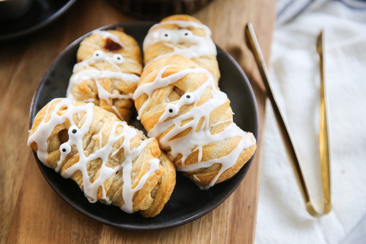 Crescent rolls decorated as mummies with candy eyes peeking out, perfect for a Halloween treat.