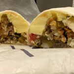 Cross-section of Braum's Grande Breakfast Burrito, a hearty fast food breakfast option near you, showing layers of eggs, sausage, pepper jack cheese, jalapenos, and hash browns.