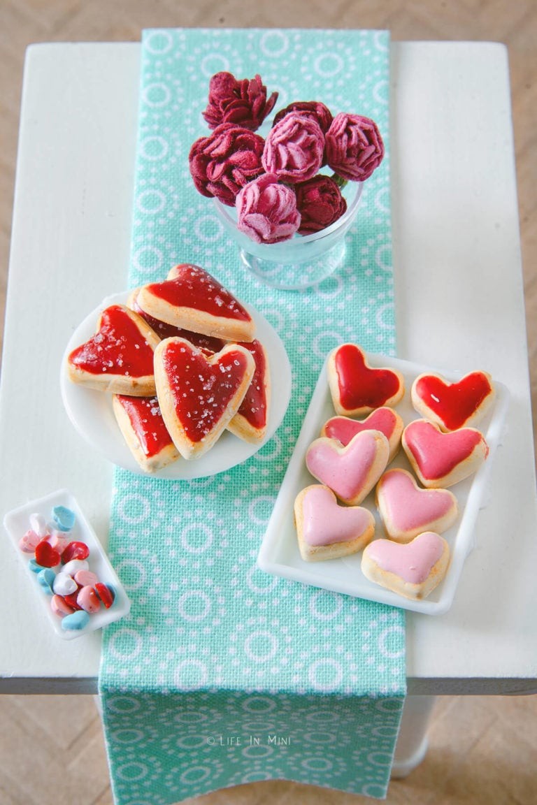 Delicate miniature Valentine's Day heart cookies crafted from polymer clay, arranged on a petite dollhouse table.